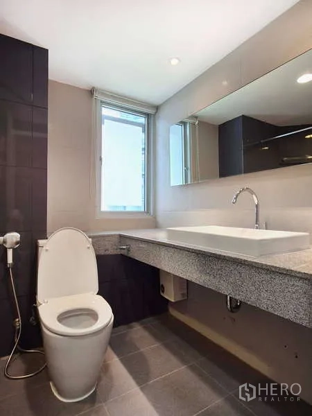 Condominium for rent in Yan Nawa, Bangkok - Bathroom with window, vessel sink on stone counter and modern fixtures.