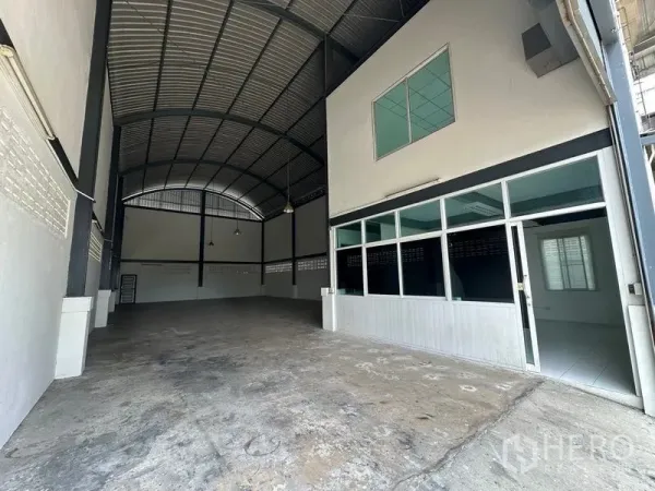 Factory for rent in Bang Bua Thong, Nonthaburi - Spacious factory floor with high arched steel roof, concrete slab and glass-partitioned office at the front.