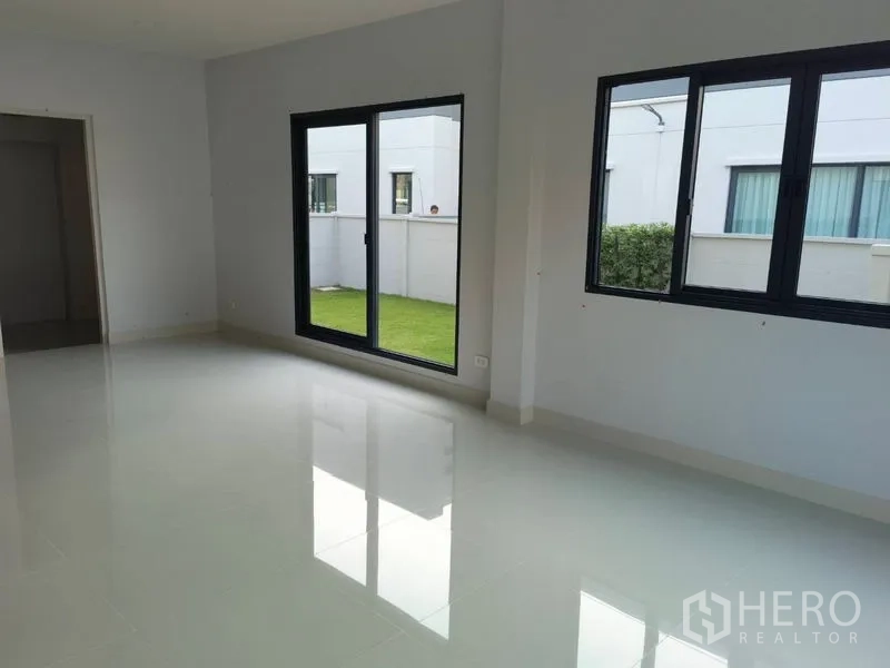 Detached House for rent in Bang Phli, Samut Prakan - Bright living area with glossy tile floors and sliding doors opening to the lawn.
