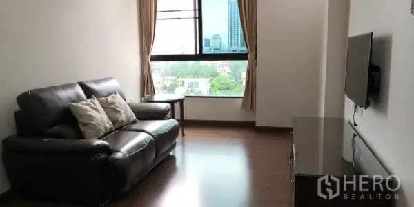 公寓 出租在Sathon, Bangkok - 沙吞公寓明亮客厅，皮沙发、壁挂电视与大窗城市景观