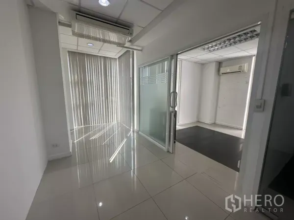 สำนักงาน ให้เช่าในHuai Khwang, Bangkok - โถงทางเดินพร้อมประตูกระจกบานเลื่อนไปยังห้องทำงานส่วนตัว มีม่านแนวตั้งและไฟดาวน์ไลท์