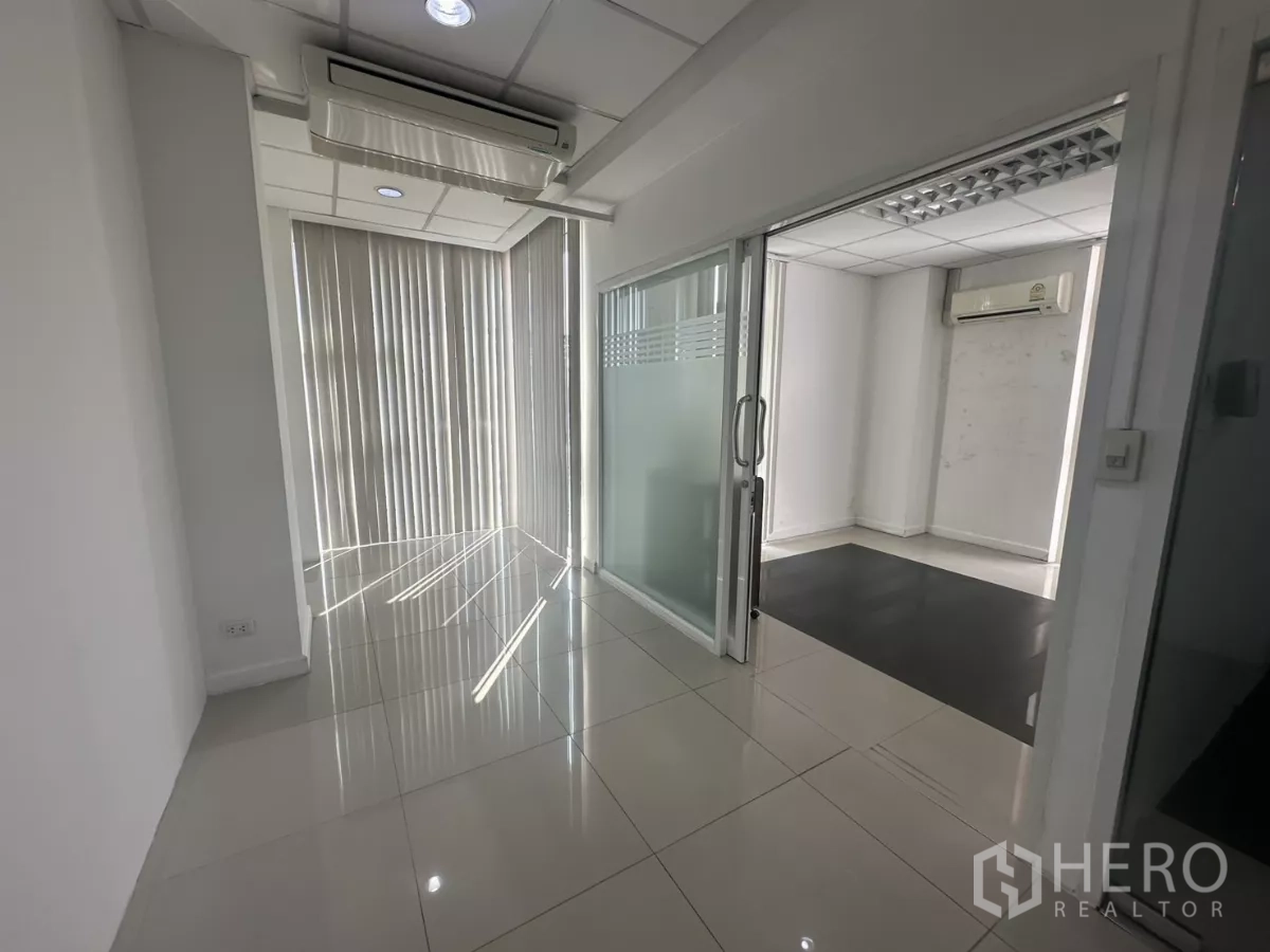 สำนักงาน ให้เช่าในHuai Khwang, Bangkok - โถงทางเดินพร้อมประตูกระจกบานเลื่อนไปยังห้องทำงานส่วนตัว มีม่านแนวตั้งและไฟดาวน์ไลท์