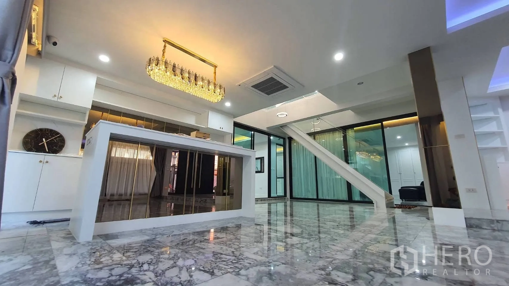 Detached House for rent in Lat Phrao, Bangkok - Dining island under crystal chandelier in bright living space.