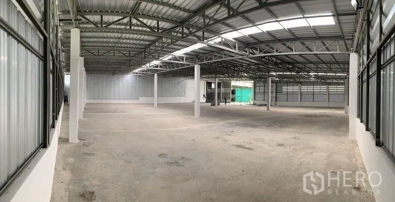 货栈 出租在Mueang Pathum Thani, Pathum Thani - 高挑开阔的仓库全景，结构立柱与金属围护清晰可见。