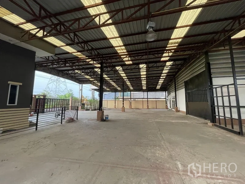 Factory for rent in Lat Lum Kaeo, Pathum Thani - Open-sided warehouse with a wide concrete yard and sliding gates.
