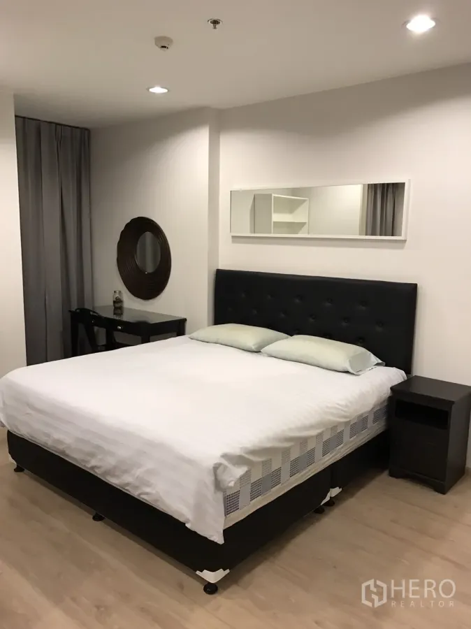 公寓 出租或出售在Ratchathewi, Bangkok - 明亮卧室，软包床头、长条镜、床头柜与浅色木地板
