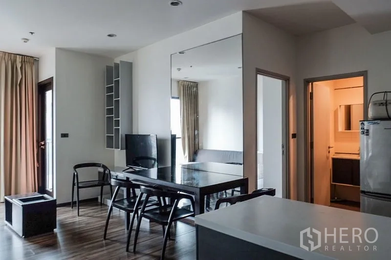 Condominium for rent in Khlong Toei, Bangkok - Cozy second bedroom with mattress, layered drapes and natural light from a corner window.