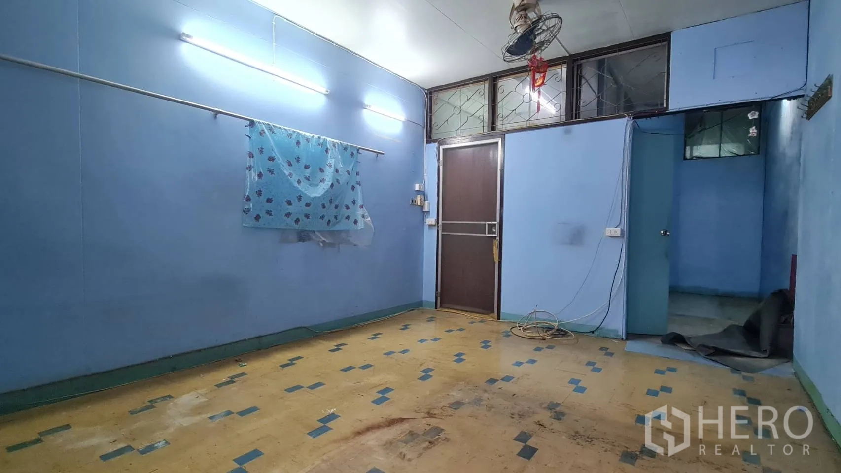 店屋 出租或出售在Watthana, Bangkok - 一层房间，蓝色墙面、日光灯、拼贴地板与木门。