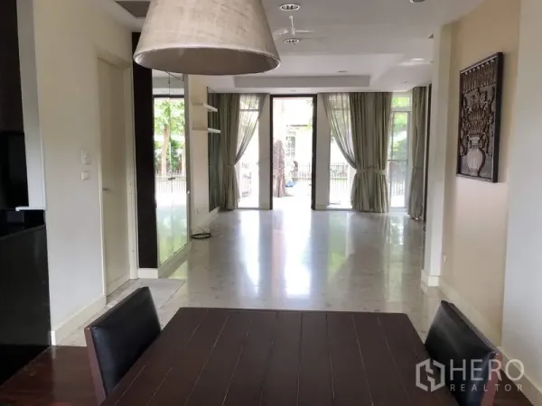 Detached House for sale in Wang Thonglang, Bangkok - Bright open-plan living area with large glass doors, curtains, and polished tile flooring.