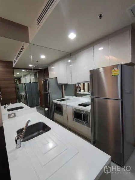Condominium for rent in Bang Rak, Bangkok - Sleek kitchenette with stainless refrigerator and ample storage.