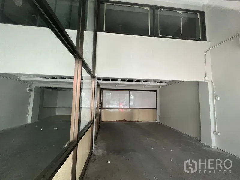 店屋 出租在Khlong Toei, Bangkok - 一层宽敞门店区域，夹层窗与后部玻璃隔间清晰可见。