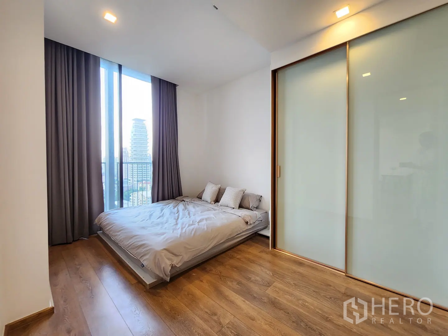 Condominium for rent in Watthana, Bangkok - Bedroom with floor‑to‑ceiling window, city view balcony and frosted glass closet doors.