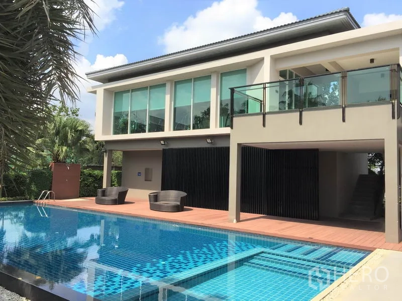 Detached House for rent in Saphan Sung, Bangkok - Estate clubhouse with large outdoor swimming pool, sun deck and glass-fronted lounge.