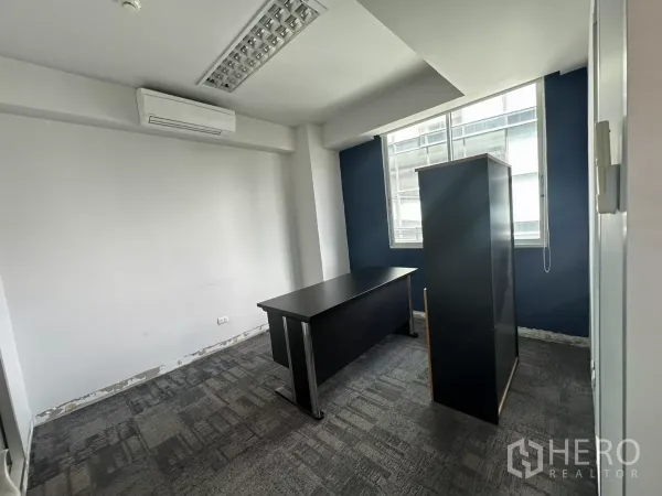 办公空间 出租在Watthana, Bangkok - 紧凑经理室，蓝色特色墙、地毯铺装，窗边自然采光。