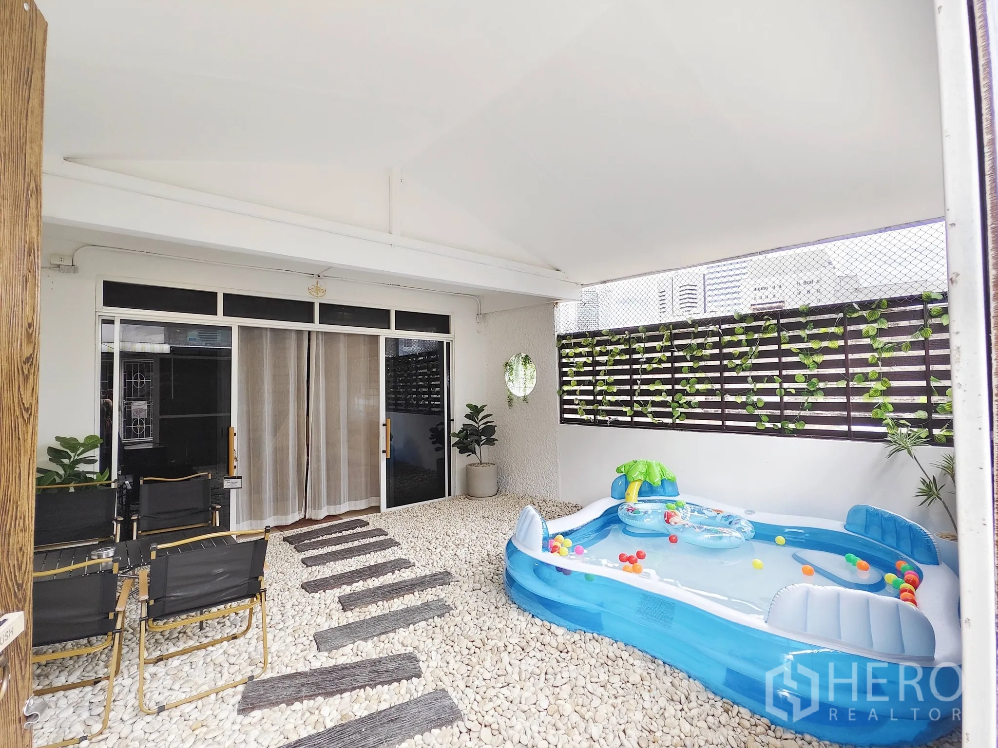 Townhouse for rent in Din Daeng, Bangkok - Covered patio with white pebble garden, walkway planks and an inflatable splash pool.
