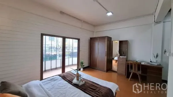 联排别墅 出租或出售在Chatuchak, Bangkok - 宽敞卧室，推拉玻璃门通向阳台，配衣柜与书桌