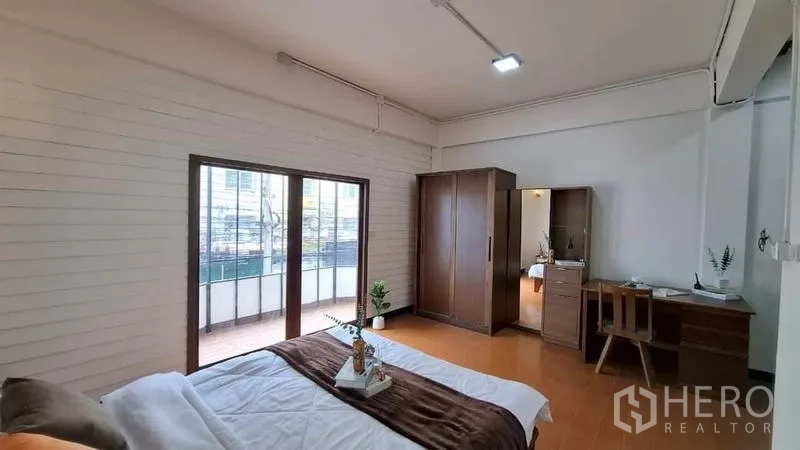 联排别墅 出租或出售在Chatuchak, Bangkok - 宽敞卧室，推拉玻璃门通向阳台，配衣柜与书桌