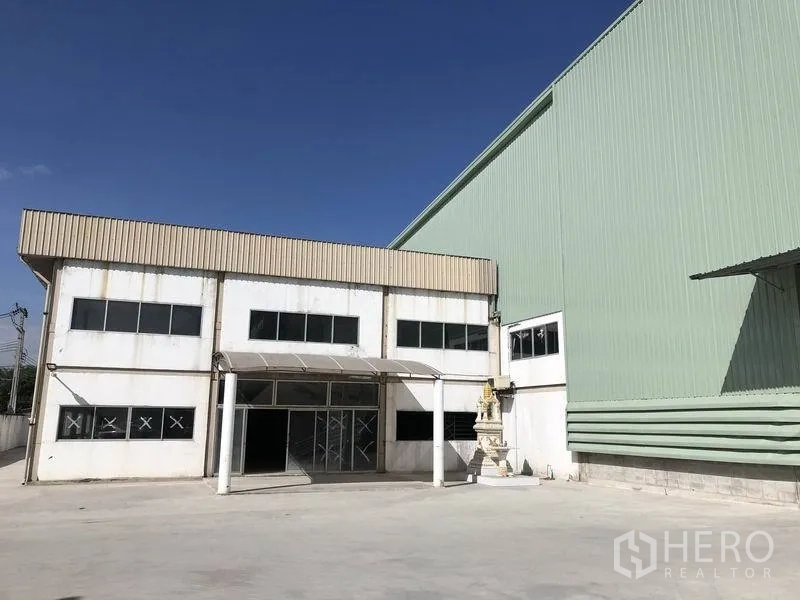 Factory for rent in Bang Phli, Samut Prakan - Exterior of a large green metal-clad factory with a two-storey office block and wide concrete yard in Bang Phli.