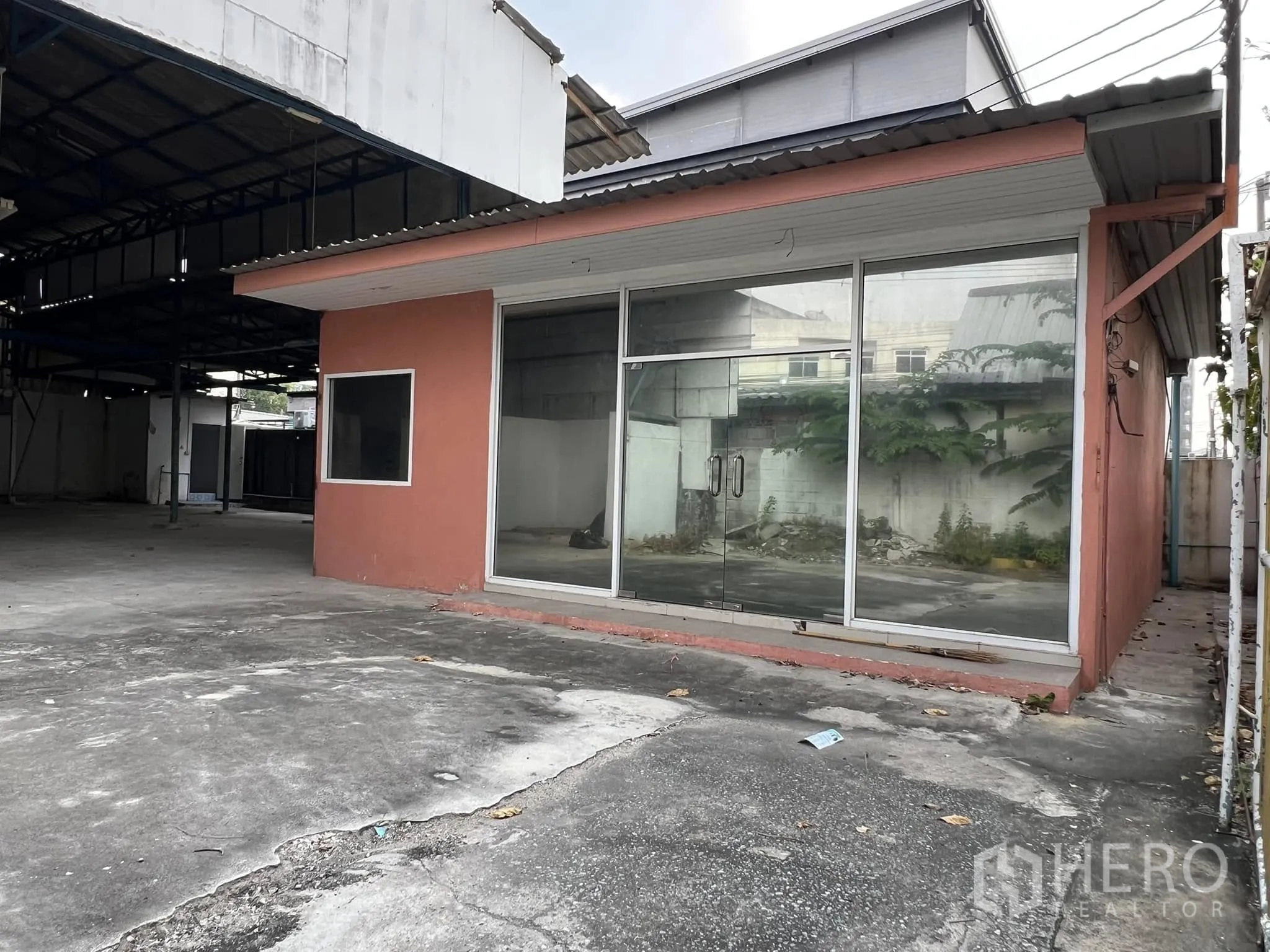 Warehouse for rent in Lat Phrao, Bangkok - Facade of the standalone office with full-height glass panels next to the covered bay.