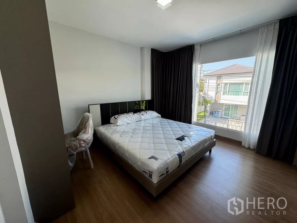 Detached House for rent in Bang Phli, Samut Prakan - Master bedroom with a large picture window, blackout curtains and wood floors.