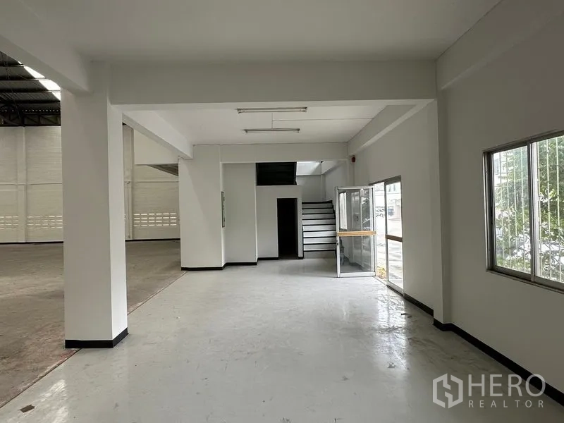 Factory for rent in Khlong Luang, Pathum Thani - Ground-floor office and reception area with glass entry, windows and stairs beside the warehouse.