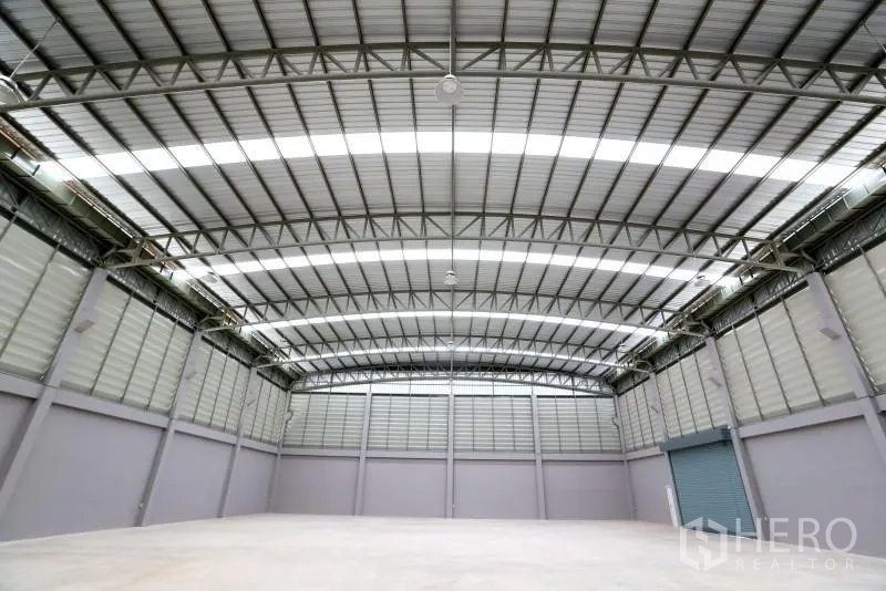 Factory for rent or sale in Bang Bo, Samut Prakan - Empty warehouse interior showing long-span trusses and bright skylight strips.