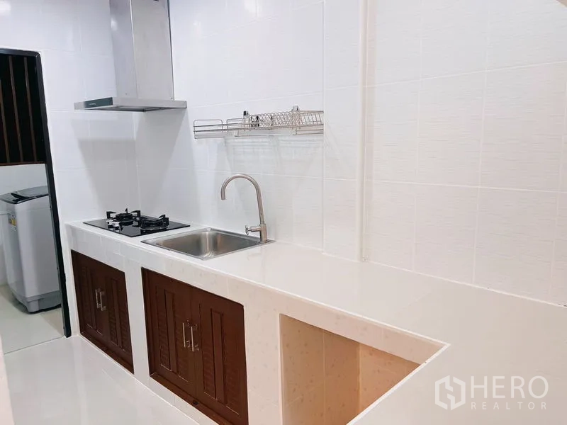 Townhouse for rent in Huai Khwang, Bangkok - Galley kitchen with extractor hood, sink and space for appliances.