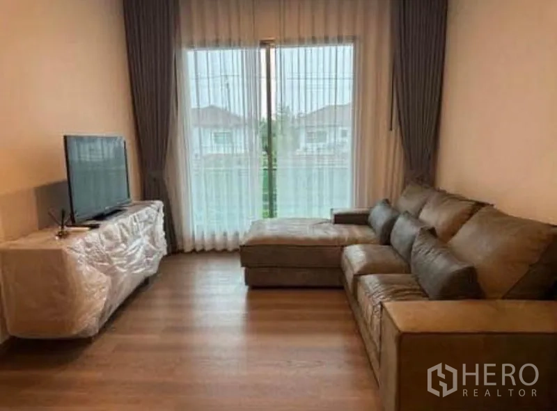 Detached House for rent - Living room with L-shaped sofa, TV console, and sliding doors with sheer curtains.