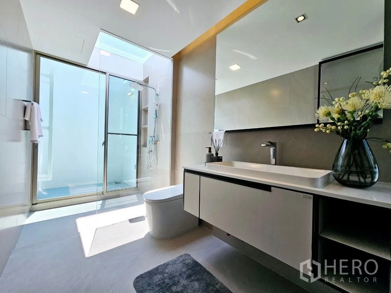 Detached House for rent in Saphan Sung, Bangkok - Bright bathroom with skylight, glass shower, and long vanity.