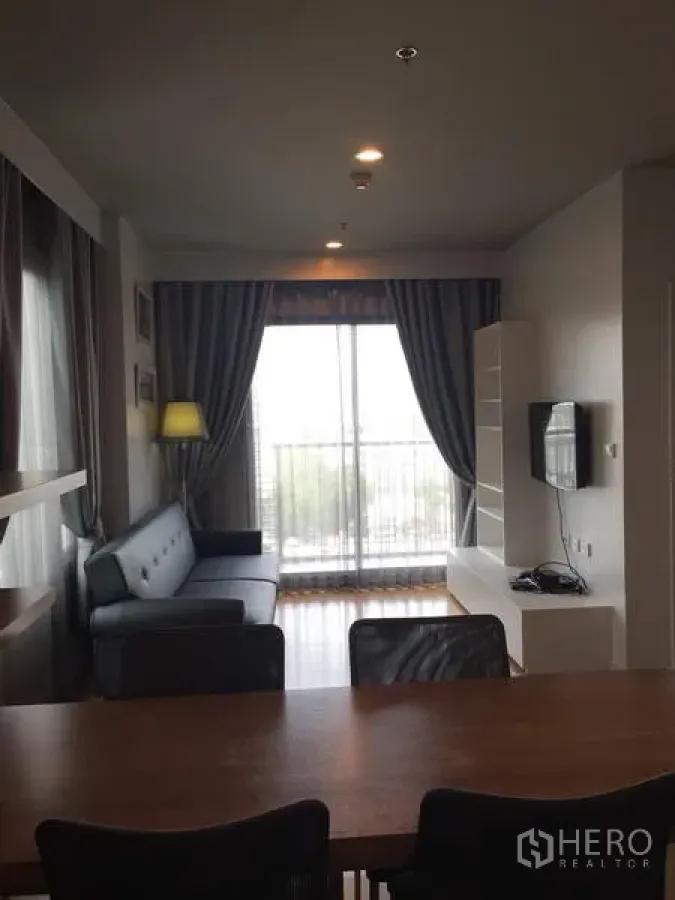 公寓 出租在Watthana, Bangkok - 客厅采光充足，沙发、电视墙与落地阳台，靠近BTS On Nut的瓦塔那区公寓
