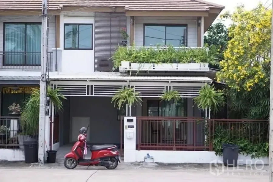 Townhouse for rent - Two-storey townhouse facade in Suan Luang, Bangkok with carport, balcony planters and front gate.