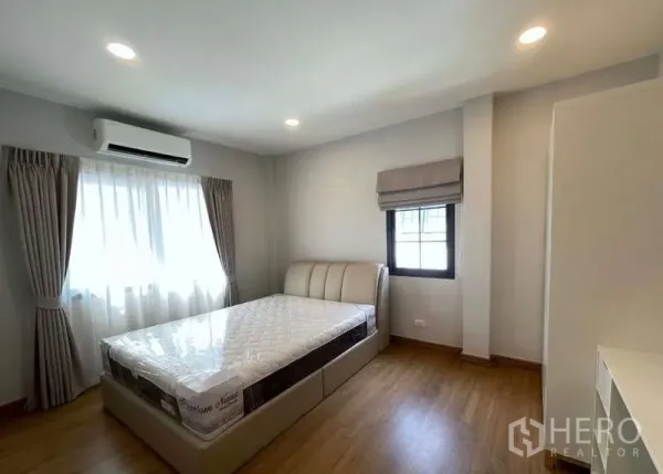 บ้าน ให้เช่าในBang Phli, Samut Prakan - ห้องนอนสว่างพร้อมเครื่องปรับอากาศ เตียง และผ้าม่านบนพื้นไม้