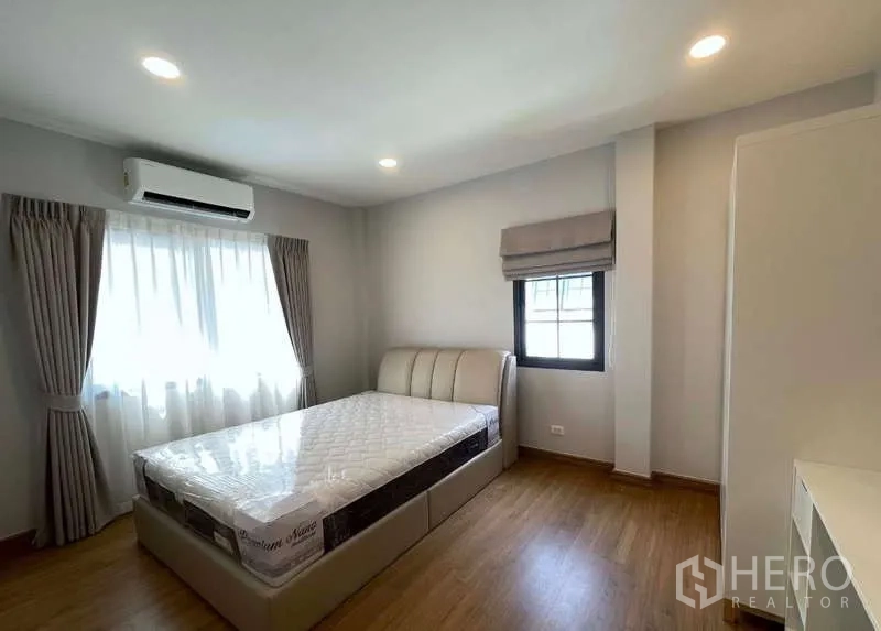 บ้าน ให้เช่าในBang Phli, Samut Prakan - ห้องนอนสว่างพร้อมเครื่องปรับอากาศ เตียง และผ้าม่านบนพื้นไม้
