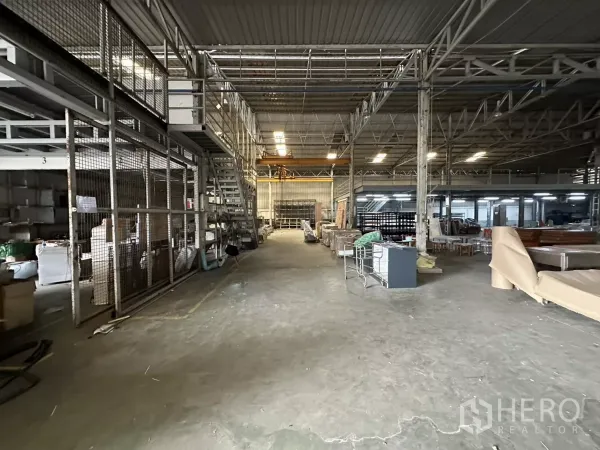 Warehouse for rent in Yan Nawa, Bangkok - Warehouse interior with mezzanine stairs, mesh partitions and storage aisles under a steel truss roof.