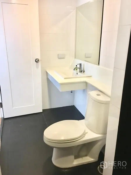 Condominium for rent in Watthana, Bangkok - Clean white bathroom with vanity, mirror and toilet.