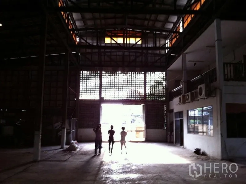 Factory for rent in Khlong San, Bangkok - High-roof factory interior with steel trusses, large entry and mezzanine offices.