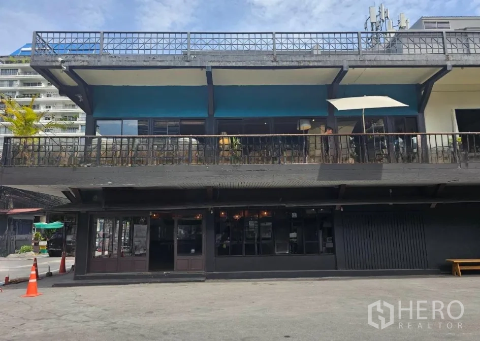 Retail Space for rent in Watthana, Bangkok - Two-storey commercial building with a large balcony terrace above and a wide forecourt parking area.