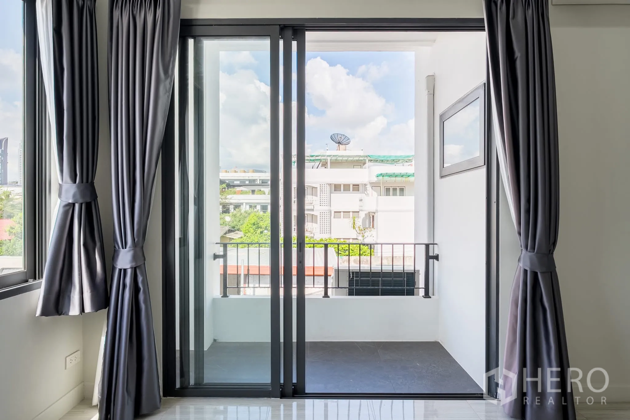Home Office for rent in Khlong Toei, Bangkok - Sliding glass doors opening to a small balcony with urban views and railing.