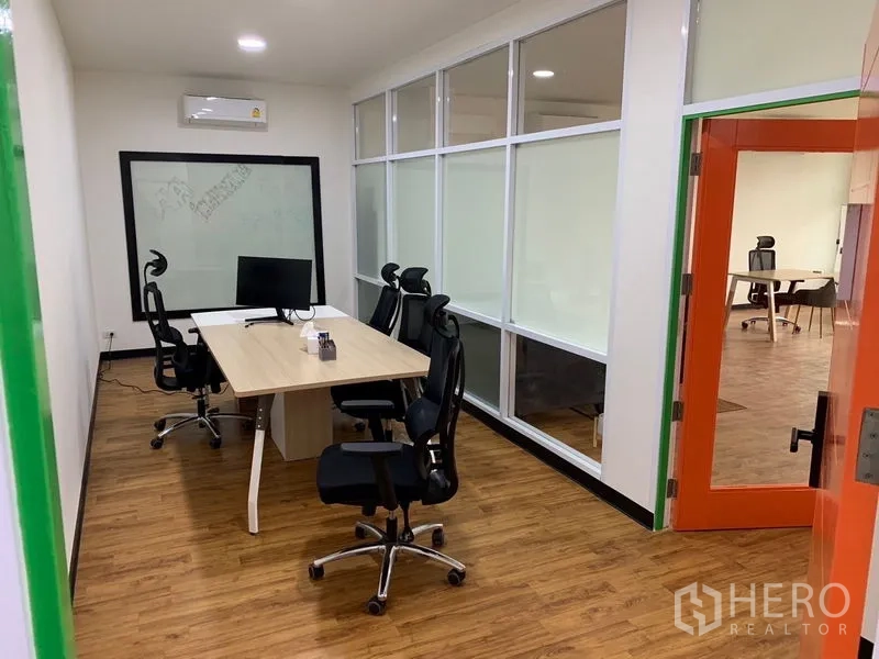 办公空间 出租在Khlong Toei, Bangkok - 玻璃隔断会议室，人体工学椅与办公桌，旁有橙色门。