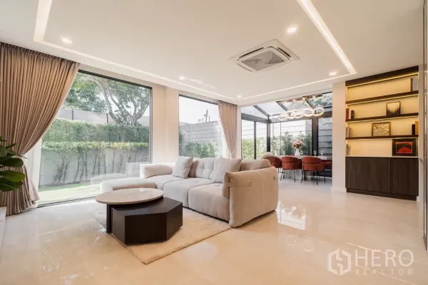 Detached House for rent or sale in Prawet, Bangkok - Open-plan lounge with floor-to-ceiling windows overlooking a private garden