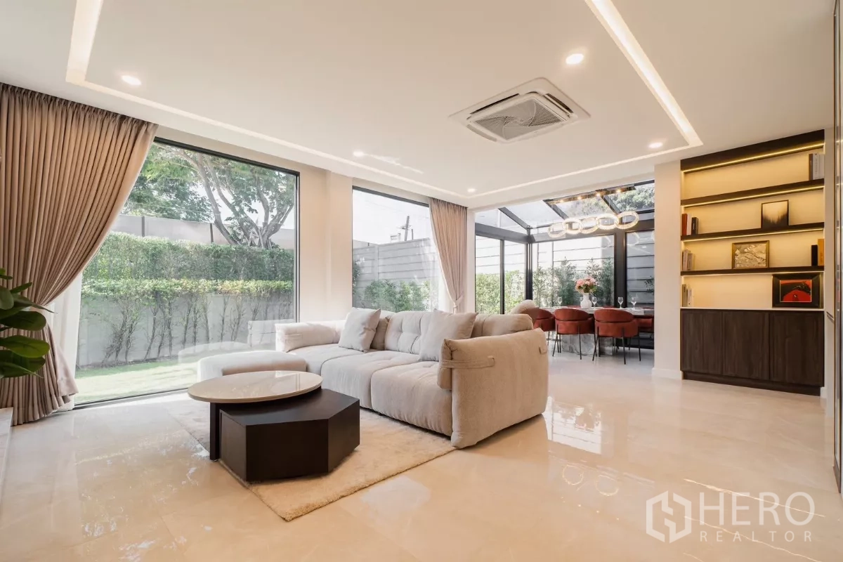 Detached House for rent or sale in Prawet, Bangkok - Open-plan lounge with floor-to-ceiling windows overlooking a private garden