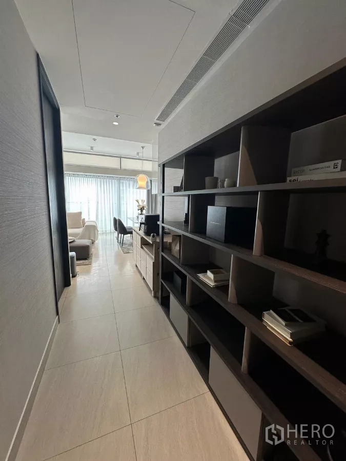 Condominium for rent in Bang Rak, Bangkok - Entry corridor with built-in shelving leading toward a light-filled lounge and dining space.