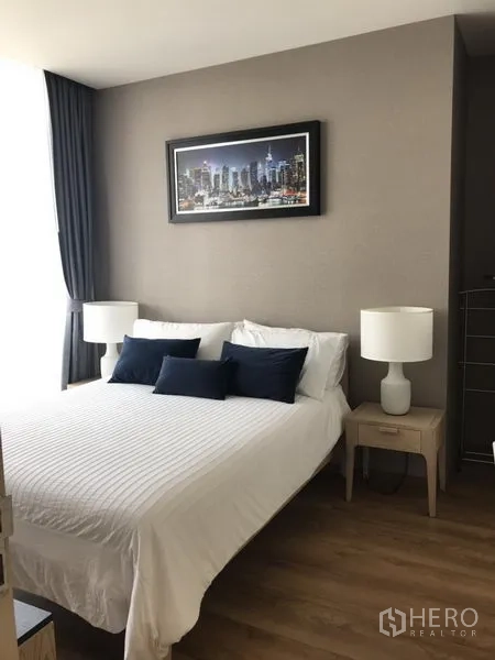 公寓 出租在Khlong Toei, Bangkok - 主卧配白色床品、床头灯与大窗帘窗，采光充足。