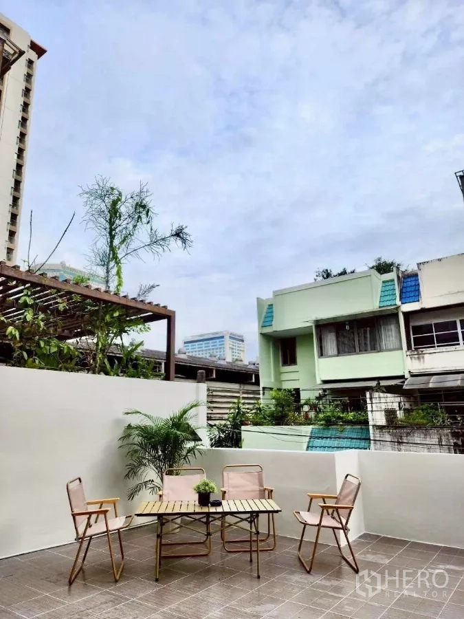 Townhouse for rent in Huai Khwang, Bangkok - Outdoor terrace with table and four chairs, potted plants and privacy walls.