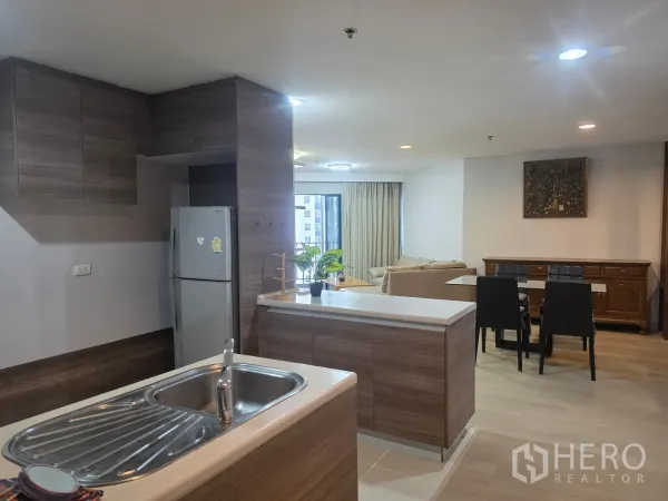 Condominium for rent in Huai Khwang, Bangkok - Open kitchen with island sink, refrigerator, and outlook to dining area.