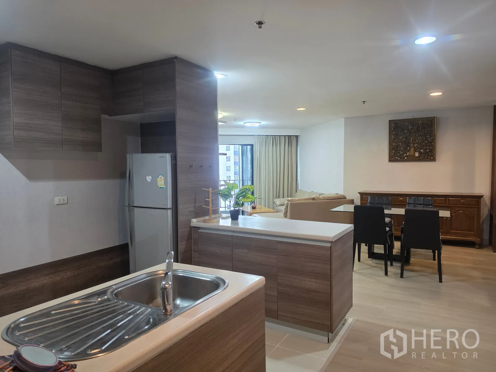 Condominium for rent in Huai Khwang, Bangkok - Open kitchen with island sink, refrigerator, and outlook to dining area.