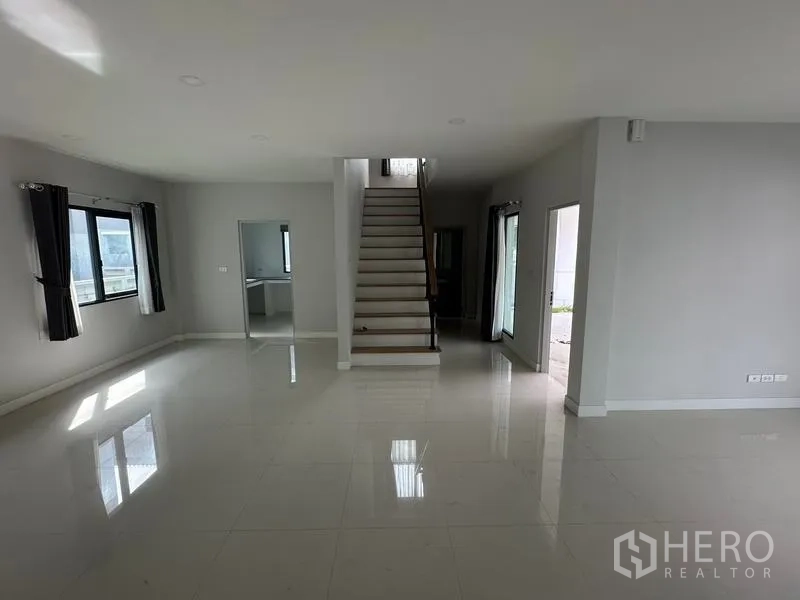 Detached House for sale in Nonthaburi - Central staircase in an airy living area with polished tile floors and natural light.