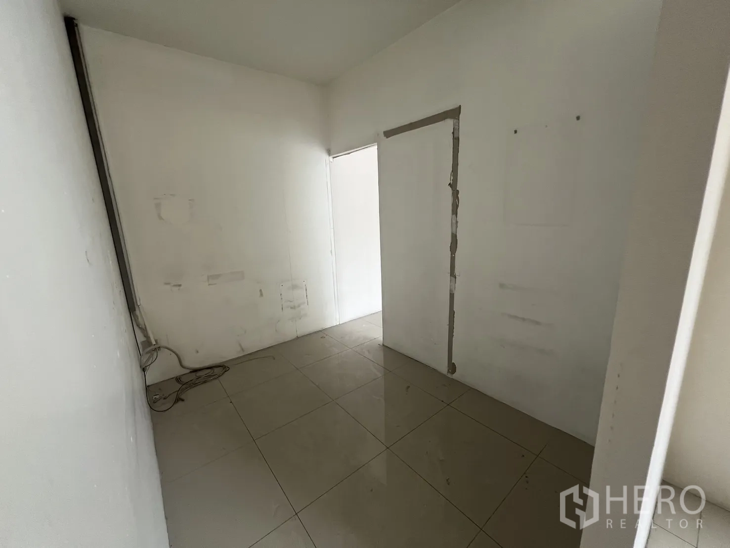 零售空间 出租在Khlong Toei, Bangkok - 走廊角落，瓷砖地面与修补痕迹。