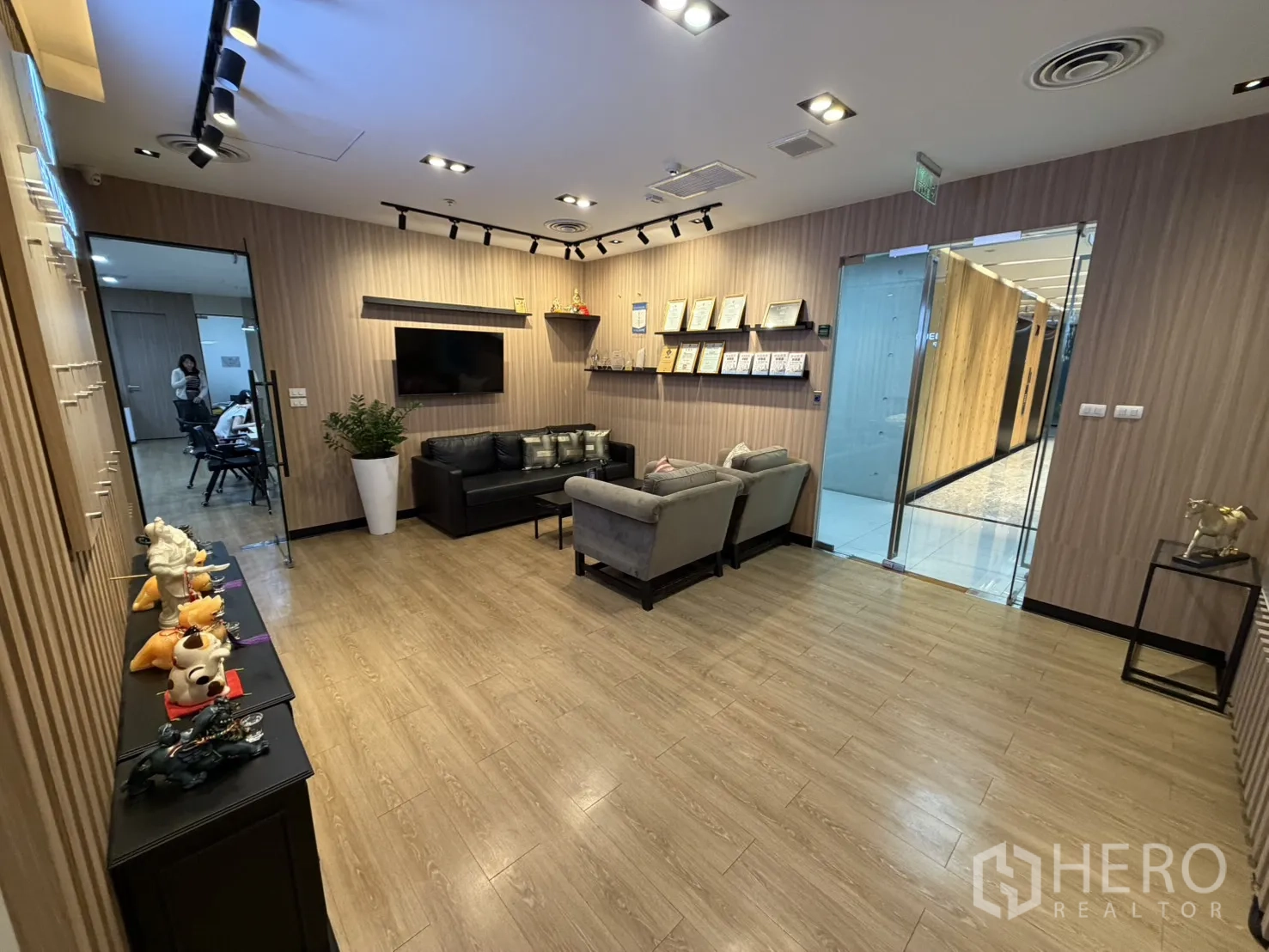 办公室 for rent in Khlong Toei, Bangkok - 现代办公室接待区，配有沙发、墙挂电视、木质墙面与玻璃门。