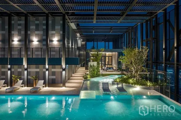 Condominium for rent in Ratchathewi, Bangkok - Rooftop swimming pool with loungers, greenery and ambient night lighting.